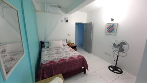 a small bedroom with a bed and a fan at Cozy vacation retreat with free parking in Roseau