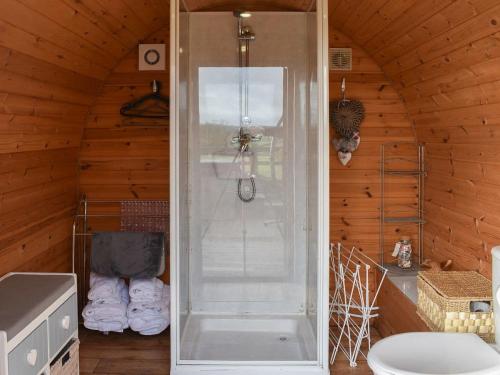 a shower in a wooden room with a toilet at Rivendell Glamping Pods in Holsworthy