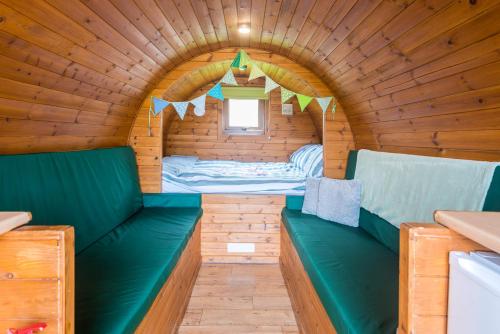 Habitación pequeña con asientos verdes en una cabaña de madera. en Rivendell Glamping Pods, en Holsworthy