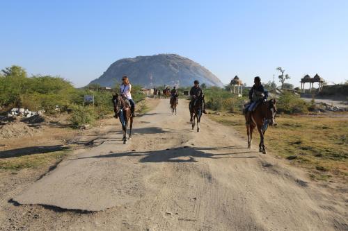 a group of people riding horses down a dirt road at The Rawla Narlai - A Luxury Heritage Stay in Leopard Country in Nārlāi