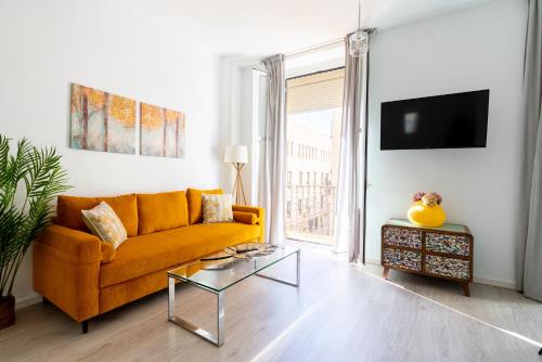 uma sala de estar com um sofá amarelo e uma mesa em Apartments Olé - Tetuán em Sevilha