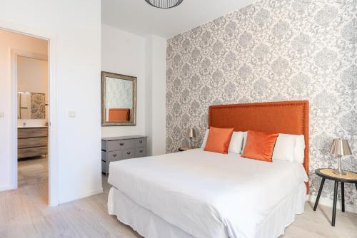 a bedroom with a large white bed with orange pillows at Tetuán Olehousing in Seville