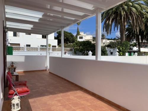 a balcony with a red chair and a white wall at Casa Jasmin Haria in Haría