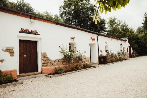 a white building with a door and some plants at Penzion Na Fojtství in Zašová