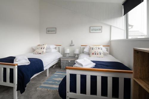 two beds in a room with white walls at Rivage - Modern Maisonette in Deganwy