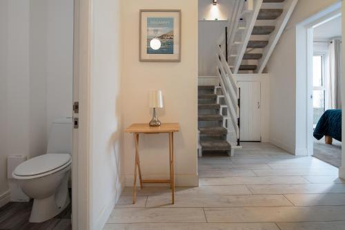 a bathroom with a toilet and a stairway at Rivage - Modern Maisonette in Deganwy