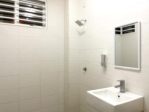 La salle de bains blanche est pourvue d'un lavabo et d'un miroir. dans l'établissement Muslim Homestay Raudhatul Jannah Bandar Sri Sendayan, à Seremban