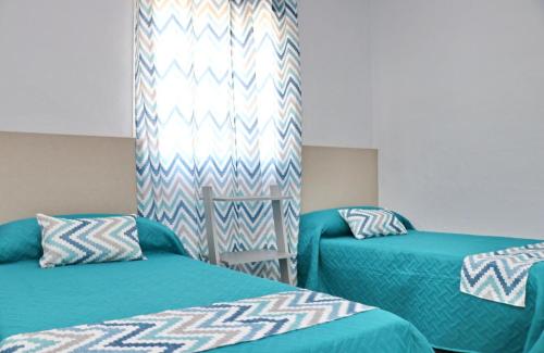 コニル・デ・ラ・フロンテーラにあるChalet Lobitaのベッドルーム1室(青と白のシーツが備わるベッド2台付)