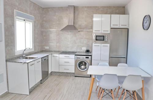 a kitchen with white appliances and a table and chairs at Chalet Lobita in Conil de la Frontera