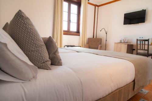 a bedroom with a white bed with pillows and a television at Hotel El Tejar & Spa in Vilaflor