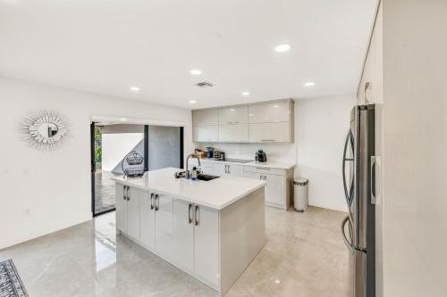 a kitchen with white cabinets and a refrigerator at Sandals Beach Cottage in Fort Lauderdale