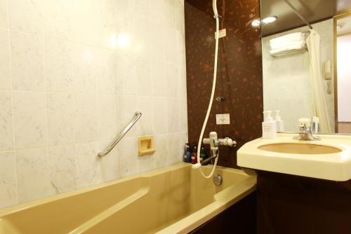 a bathroom with a sink and a bath tub and a sink at KOKO HOTEL Numazu Ekimae in Numazu
