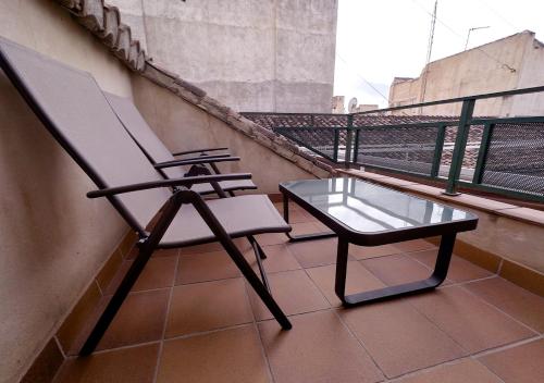 a chair and a glass table on a balcony at ISA Granada in Granada