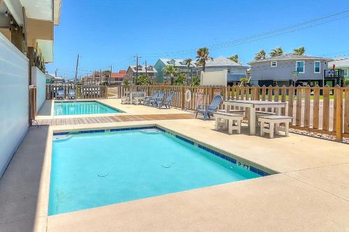 una piscina con mesa, sillas, mesa de picnic y mesa de picnic en Stack Overflow, en Port Aransas