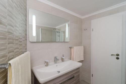 a white bathroom with a sink and a mirror at Sea view apartment 10 minutes walk from old city in Dubrovnik