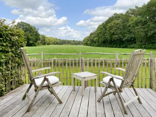 two chairs and a table on a wooden deck at B&B De Paenhoeve in Eksel