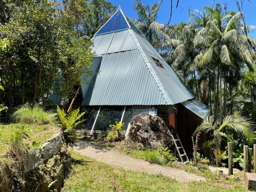 una pequeña casa con techo de estaño en un jardín en Aruna espaco regenerativo, en Florianópolis