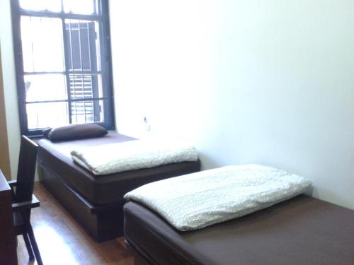 a room with two beds and a window at Phuket Sunny Hostel in Phuket Town