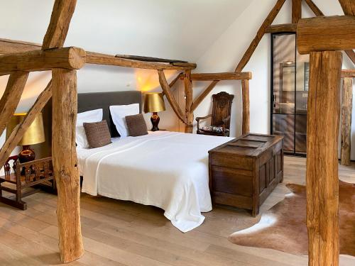 a bedroom with a large white bed with wooden beams at B&B De Paenhoeve in Eksel