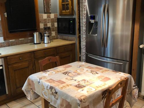 une cuisine avec une table et un réfrigérateur en acier inoxydable dans l'établissement Chalet 5 pièces, 10 pers avec balcons et jardin, Valloire, proche télésiège et navette gratuite - FR-1-263-465, à Valloire