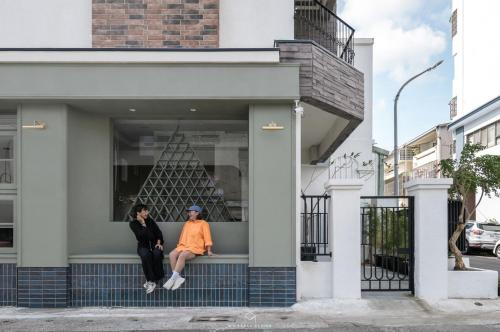 two women sitting on a window sill of a building at 夏蕾民宿 Sunny Rest in Taitung City