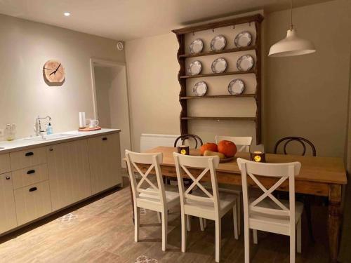 a kitchen with a wooden table with chairs and a bowl of fruit at La Relique ( woning voor 4 tot 6 personen ) in Bouillon