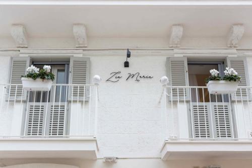 a white building with two balconies with flowers on it at Zia Maria in Fasano