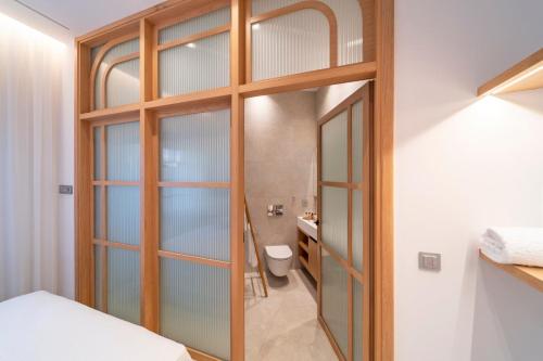 baño con una puerta de cristal que conduce a un aseo en Naillac Elite Suites en Rodas