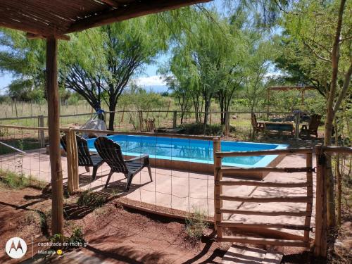 a swimming pool with two chairs and a fence at Chakana Hospedaje Rural in Villa Unión