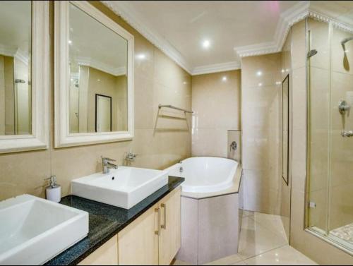 a bathroom with two sinks and a tub and a shower at The Sails Apartment in Durban