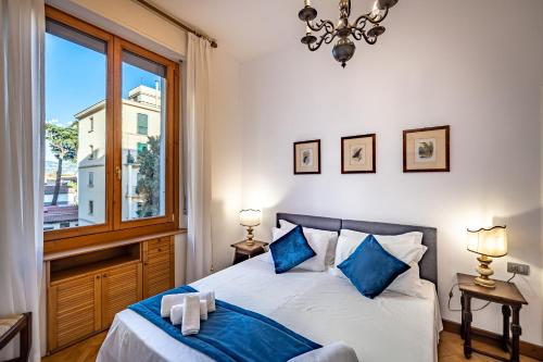 sypialnia z łóżkiem z niebieskimi poduszkami i oknem w obiekcie YiD Leopolda apt few minutes from Central Station we Florencji