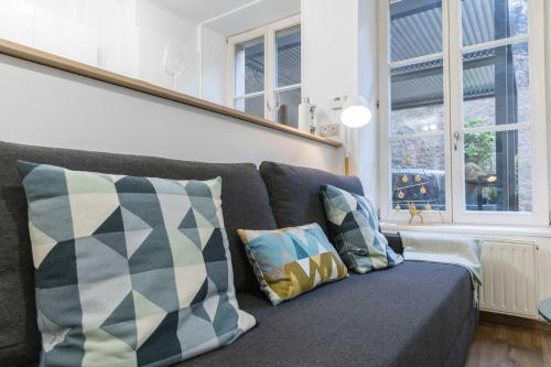 a gray couch with pillows in a living room at SPA, TERRASSE plein centre et proche gare in Metz