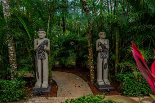two statues of men standing on a path in a garden at Leyenda Boutique Hotel & Spa in Sámara