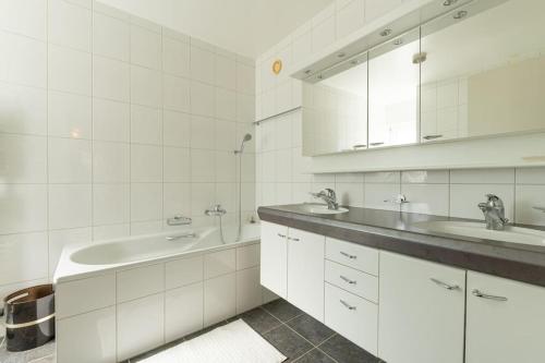 uma casa de banho branca com 2 lavatórios e um espelho em Lakeside Apartment - Grand appartement familial avec terrasses et vue panoramique em Vevey