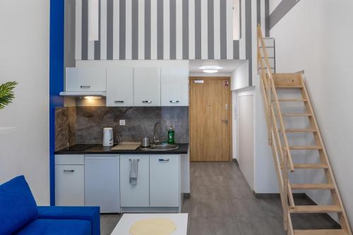 una cocina con armarios blancos y una escalera en Studia przy lotnisku od WroclawApartament-pl, en Wroclaw