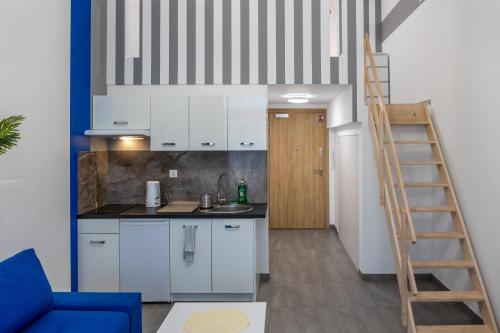 a kitchen with white cabinets and a ladder at Studia przy lotnisku od WroclawApartament-pl in Wrocław