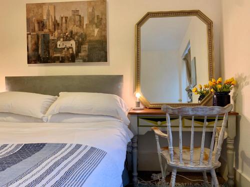 a bedroom with a bed and a mirror and a chair at Flat Near Richmond Upon Thames in Richmond