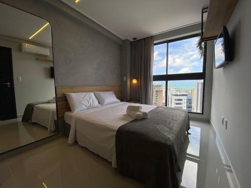 Habitación de hotel con cama y ventana grande en Bela Hospedagem - Lindo apt no One Way com vista incrível do mar, en João Pessoa