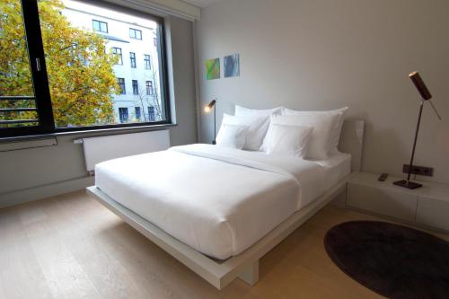 a white bed in a room with a large window at SANA Berlin Residence in Berlin