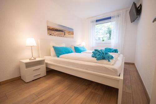 um quarto com uma grande cama branca com almofadas azuis em Haus Kirsten Haus Kirsten FeWo 1 em Duhnen