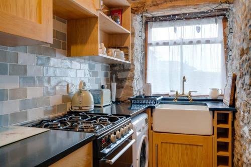 a kitchen with a stove top oven next to a sink at Penny Post Cottage in Warton