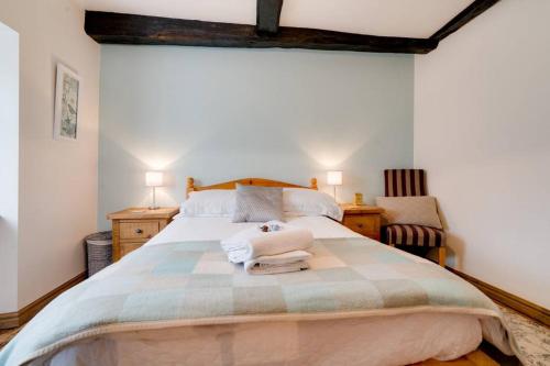 a bedroom with a large bed with two towels on it at Penny Post Cottage in Warton
