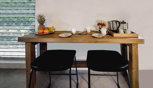 a wooden table with two chairs and a bowl of fruit at The Gatehouse. Cool bolthole. Walk to the Marina. in English Harbour Town