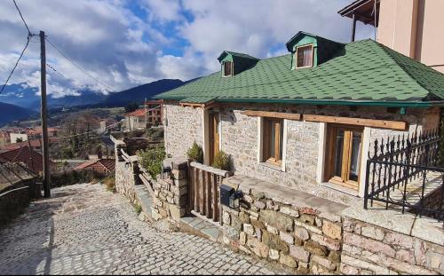 a stone house with a green roof on a street at The House in the Cobbled Road in Karpenision
