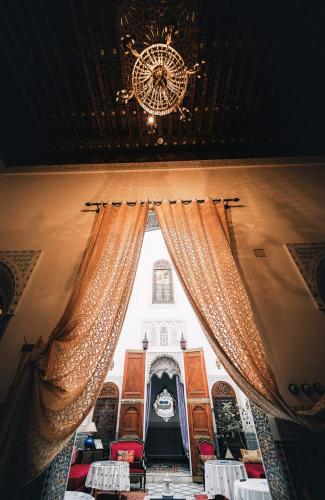 a room with a chandelier and a window with curtains at Riad Arabella in Fès