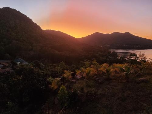 a sunset over the mountains and a body of water at Ocean View Apartment in Anse Possession