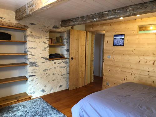 a bedroom with a bed and a stone wall at Les gîtes du Mistouflon in Planay