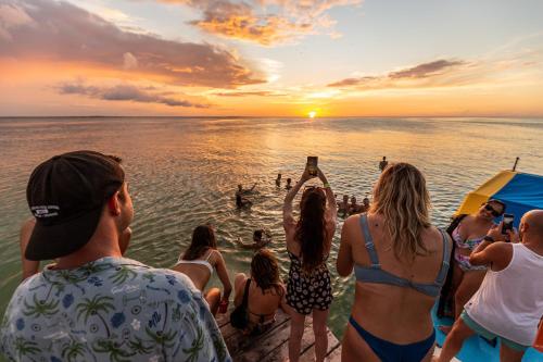 a group of people standing on a beach watching the sunset at Che Holbox Hostel & Bar Adults Only in Holbox Island