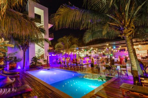 un grupo de personas sentadas alrededor de una piscina por la noche en Che Holbox Hostel & Bar Adults Only, en Isla Holbox