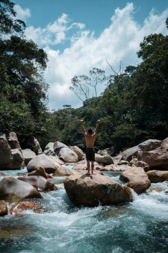 a man standing on a rock in a river at La Perla Negra - Black Pearl Eco Hostel in San Rafael